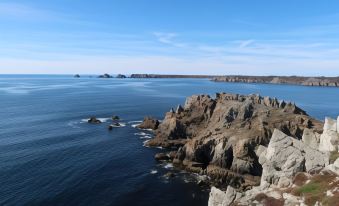 a rocky coastline with a body of water in the background , creating a serene and picturesque scene at Lagrange Vacances le Hameau de Peemor PEN