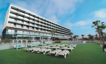 a large hotel with a swimming pool and numerous lounge chairs in front of it at Hotel Dos Playas