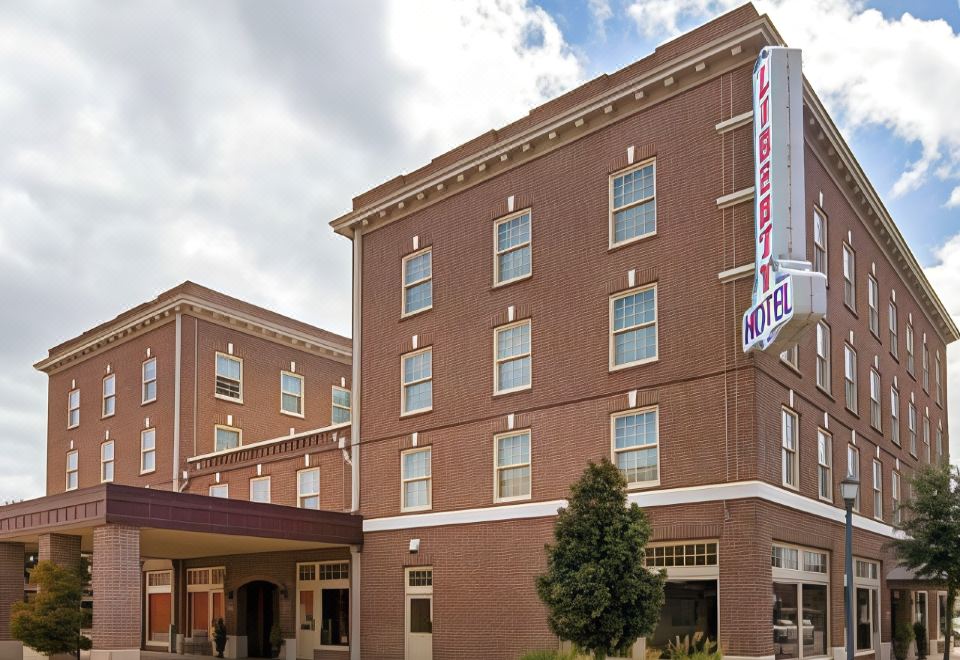 a large brick building with a hotel sign on the front , surrounded by trees and other buildings at Liberty Hotel, Ascend Hotel Collection