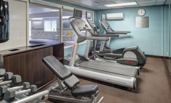a well - equipped gym with various exercise equipment , including treadmills and weight machines , in a well - lit room at Fairfield Inn & Suites Tustin Orange County