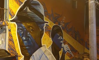 a mural of two men is painted on the side of a building , with cars parked nearby at Majesty Palm