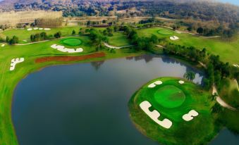 aerial view of a golf course with two green holes and a pond in the background at Gassan Khuntan Golf & Resort