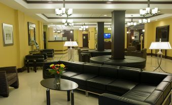 a spacious room with black leather couches , a dining table , and chairs , as well as a bar area at Holiday Inn Johnstown-Downtown
