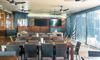 a dining room with wooden tables and chairs , along with a television mounted on the wall at Peppermill Inn Motel