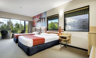 a modern hotel room with two beds , a desk , and a window offering a view of the city at Kingfisher Bay Resort