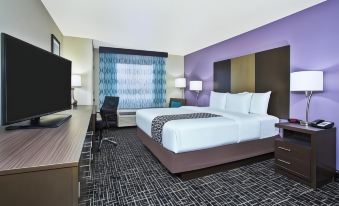 a large bed with white linens is in a room with purple walls and a black and white checkered floor at La Quinta Inn & Suites by Wyndham Fairborn Wright-Patterson