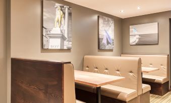 a dining area with a wooden table , two beige booths , and two paintings on the wall at Premier Inn Penzance