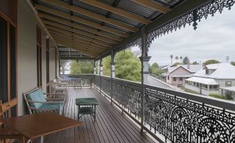 a wooden deck with a metal railing overlooks a residential area , and several benches placed on the deck at Ulmarra Hotel