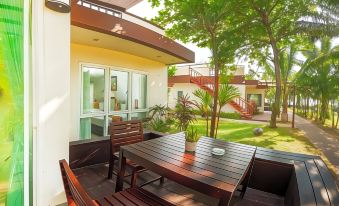 a wooden table and chairs are set up on a patio with a view of a house at Chaolao Cabana Resort