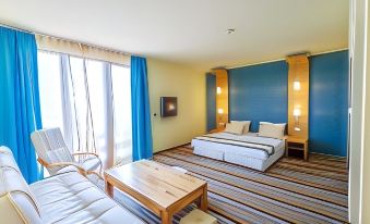 a modern hotel room with two beds , a wooden desk , and a large window with blue curtains at Mirage Hotel