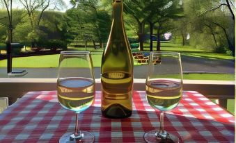 a table with two wine glasses and a bottle of wine on it , along with a picnic table nearby at Finger Lakes Bed and Breakfast
