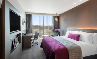 a modern hotel room with a large bed , desk , and tv , all decorated in neutral colors at Sage Melbourne Ringwood