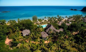a tropical resort with a large swimming pool surrounded by palm trees and a beach in the background at VOI Amarina Resort