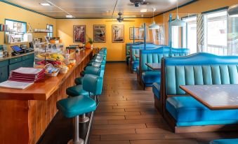 a restaurant with blue booths and tables , a wooden counter , and colorful food items on display at Yosemite Westgate Lodge