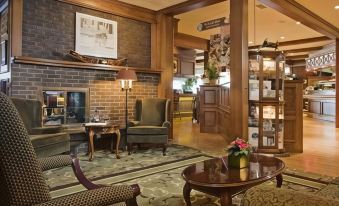 a cozy living room with wooden furniture , including a fireplace , chairs , and a couch , surrounded by other furniture at Crest Hotel