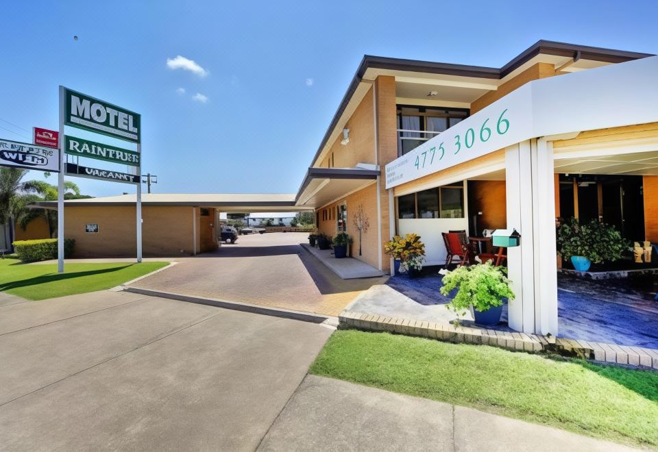 a hotel entrance with a large sign above it , indicating the name of the establishment at Raintree Motel