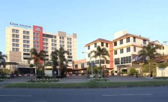 a large building with multiple floors and balconies , surrounded by palm trees on a sunny day at Grand Pasundan Convention Hotel