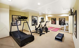 a well - equipped exercise room with various fitness equipment , including treadmills and stationary bikes , under a yellow ceiling at Clarion Hotel Bergen