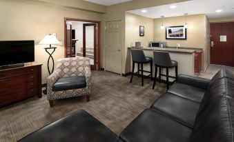 a hotel room with a living area featuring a couch , chairs , and a bar area at Bismarck Hotel and Conference Center