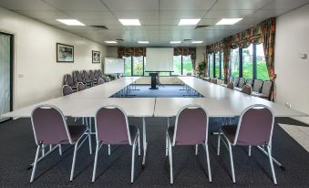 a conference room with a large table , multiple chairs , and a projector screen set up for a meeting at Best Western Mahoneys Motor Inn