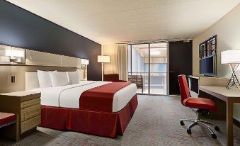 a modern hotel room with a large bed , white and red bedding , and a view of the city at Ramada by Wyndham Clarion