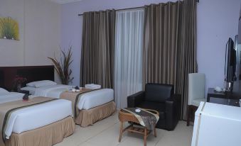 a hotel room with two beds , a chair , and a window covered in curtains , creating a cozy atmosphere at Griya Hotel
