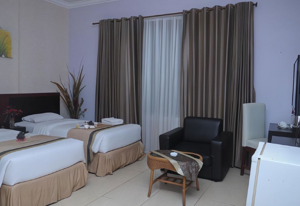 a hotel room with two beds , a chair , and a window covered in curtains , creating a cozy atmosphere at Griya Hotel