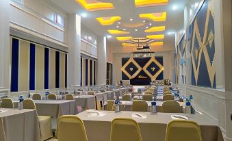 a large , well - lit conference room with multiple tables and chairs set up for a meeting or event at Nonghan Grand Hotel and Resort