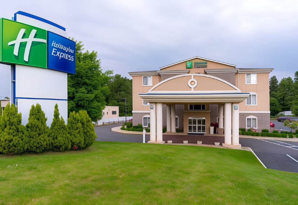 "a large building with a blue sign that reads "" holiday inn express "" is surrounded by greenery and a grassy area" at Holiday Inn Express Newington - Hartford