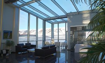 a modern living room with large windows and a view of the mountains outside , featuring black leather couches and a white coffee table at Hotel Selfoss