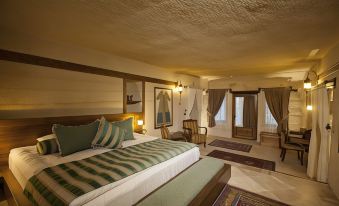 a large bed with a striped blanket is in the middle of a room with two windows at Kayakapi Premium Caves Cappadocia