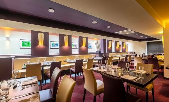 a modern restaurant with multiple dining tables , chairs , and wine glasses arranged for guests to enjoy a meal at Gloucester Robinswood Hotel, BW Signature Collection