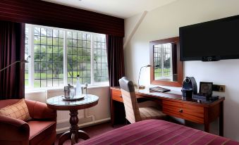 a hotel room with a large window , a bed , a chair , and a desk with a tv at Macdonald Craxton Wood Hotel