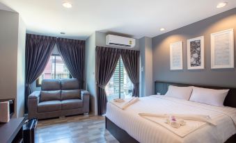 a modern bedroom with a white bed , grey curtains , and a couch in the living room at Grand Inter Hotel
