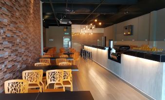 a modern restaurant with wooden tables and chairs , a bar area , and pendant lights hanging from the ceiling at Ants Hotel