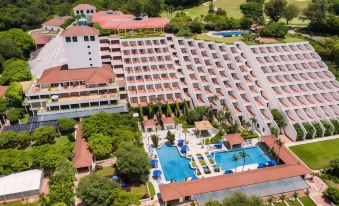 The aerial view showcases a resort with a pool and beachside cabanas on both sides at Grand Coloane Resort Macau