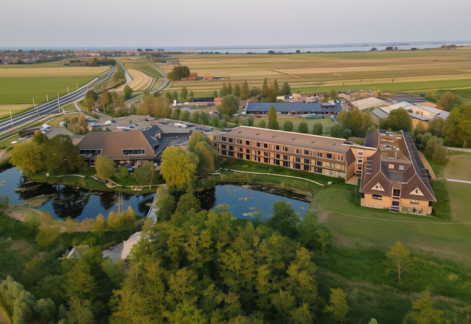 a bird 's eye view of a large resort with multiple buildings , a lake , and lush greenery at Van der Valk Volendam