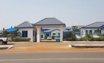 a blue and white building with a curved roof is situated on a dirt road at Blue Hill Hotel