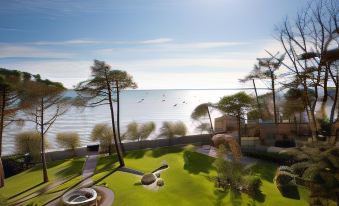 a grassy lawn with a fire pit surrounded by trees , overlooking a body of water at Villa la Tosca