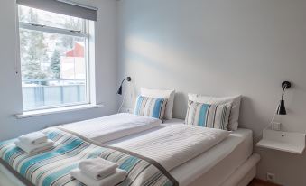 a neatly made bed with white sheets and blue and white striped pillows is shown in a bedroom at Hildibrand Apartment Hotel