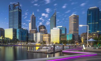 a city skyline at dusk , with tall buildings and a marina filled with boats in the foreground at Attika Hotel