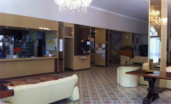 a hotel lobby with a reception desk , couches , chairs , and a chandelier hanging from the ceiling at Eden Park Hotel