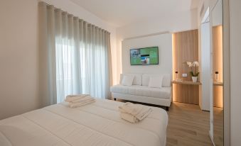 a hotel room with a white bed , couch , and tv , along with curtains and a television on the wall at Toscana Charme Resort