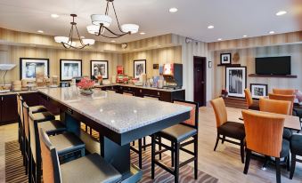 a large , open - concept kitchen and dining area with a marble island , wooden chairs , and modern lighting at Hampton Inn Ashland