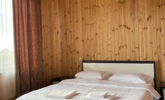 a bed with white sheets and a wooden headboard is situated in a room with wood paneling at ELION