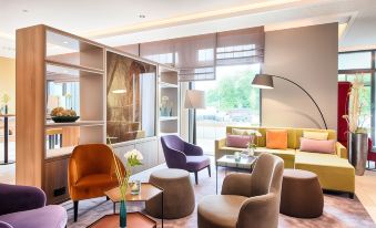 a modern living room with colorful chairs , couches , and a coffee table , creating a cozy atmosphere at Leonardo Offenbach Frankfurt