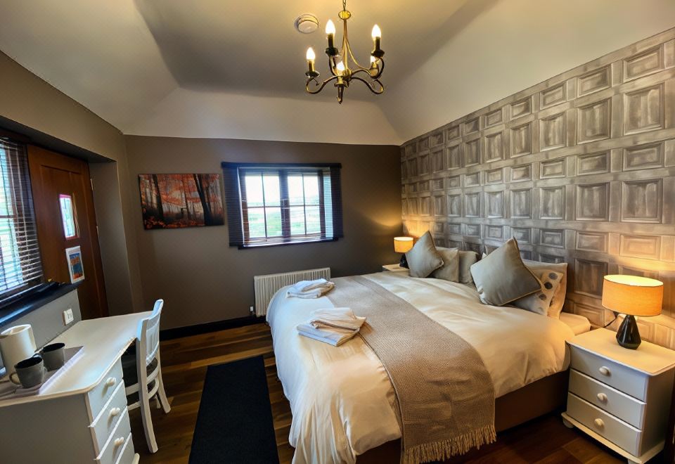 a cozy bedroom with a large bed , two chairs , and a window , decorated with a chandelier and artwork on the walls at The Mary Tavy Inn