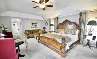 a large bedroom with a wooden bed , a couch , and a ceiling fan mounted on the wall at Sassafras Inn