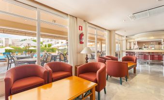 a room with multiple red chairs and tables , all facing large windows , overlooking a pool area at Linda