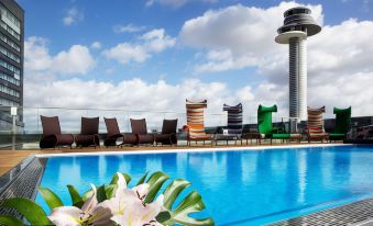 a rooftop pool with lounge chairs and a view of an airplane tower in the background at Clarion Hotel Arlanda Airport Terminal
